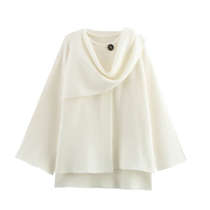 Detail view of cream white knitted shawl featuring a single button and soft wool texture