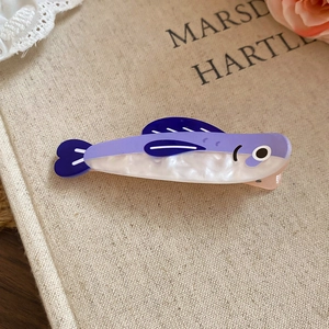 Close-up of fish-shaped acrylic hair clip with pearlescent finish and blue purple tones