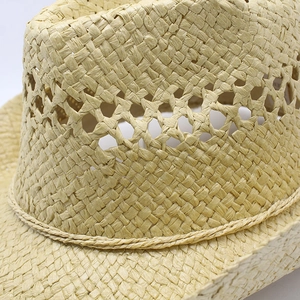 Close-up of beige woven straw hat featuring diamond cut-out vents and rope trim