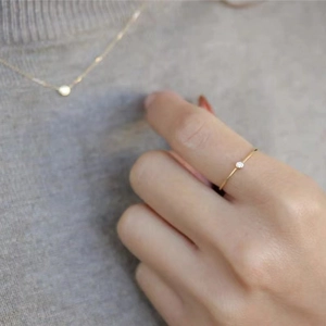 Close-up of minimalist 18K gold plated ring and necklace set with tiny round diamond