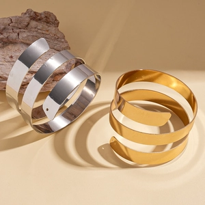 Polished gold and silver spiral arm cuffs with a geometric three-layer metal design