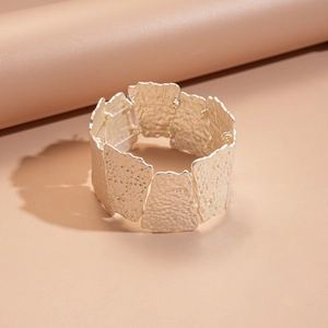 Detailed macro view of wide silver bracelet with hammered texture and irregular square pieces