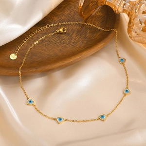 Close-up of golden stainless steel necklace with heart-shaped evil eye charms on silk