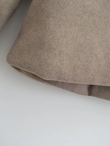 Vue macro du tissu en laine beige chiné et de la doublure intérieure soyeuse du manteau