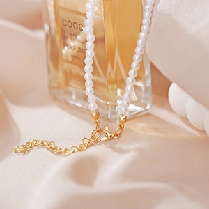 Detail of white pearl necklace featuring gold lobster clasp and heart link extension chain