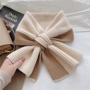 Detail of a beige and brown ribbed knit scarf tied in a bow for winter warmth