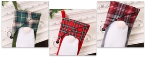 Detailed view of three festive plaid Christmas gnome stockings hanging on a white fireplace