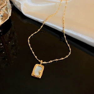 Detail of gold fishtail necklace with mother of pearl inlay on white silk backdrop