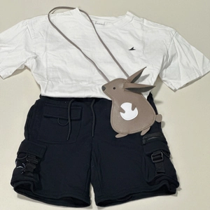 Flat lay of kids white cotton T-shirt, black cargo shorts and brown rabbit crossbody bag