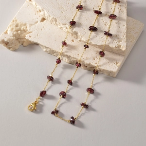 Close-up of French vintage gold chain necklace featuring irregular red garnet stones