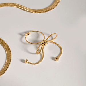 Detail of a vintage golden bow ring with snake chain texture on a minimalist white background
