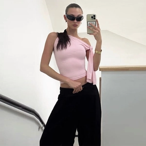 Détail du haut rose ajusté à une épaule avec nœud et pantalon large noir élégant