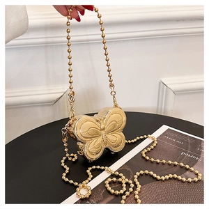 Close-up of a gold butterfly-shaped metal clutch bag with a spherical chain strap