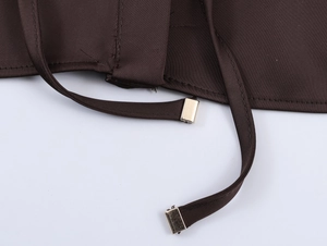 Gros plan détaillé sur le tissu en satin marron foncé avec embouts en métal doré et coutures