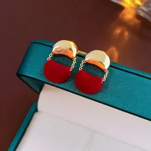 Dettaglio orecchini ad albero di Natale con velluto rosso e catene dorate