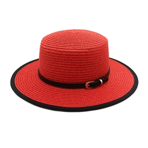 Detail of red straw hat with black leather band, gold buckle and contrasting trim