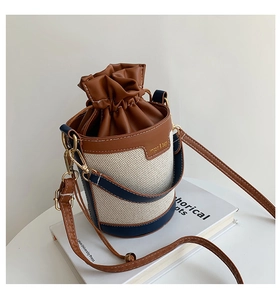 Detail of color-block bucket bag with beige canvas, brown leather trim and gold buckles