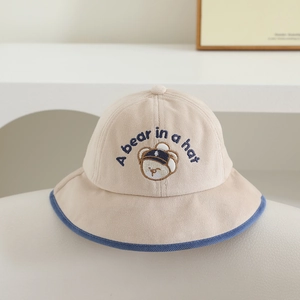 Détail du chapeau bob en velours côtelé beige pour enfant avec broderie ours et bord bleu