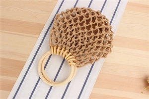 Detail of hand-woven mesh bag with round wooden handles on a rustic table