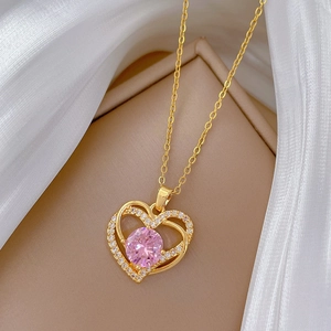 Détail du collier coeur doré avec pierre rose sur fond de soie luxueuse et raffinée