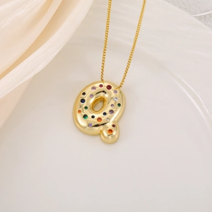 Macro shot of bubble letter Q pendant with multi-colored crystals on a gold chain