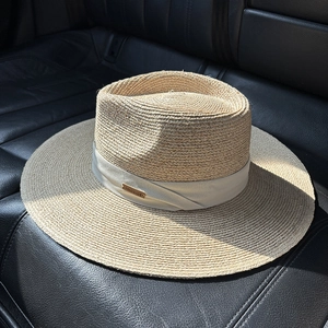 Detailed macro view of woven raffia texture and gold handmade logo plaque on sun hat