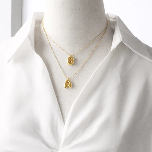 Close-up of gold-plated bubble letter A and B pendants on a delicate layered chain