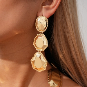 Detailed view of long triple-segment geometric gold earrings on a female model