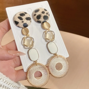 Détails de boucles d'oreilles pendantes avec imprimé léopard et anneaux tissés