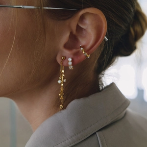 Détail de boucles d'oreilles à pompons plaquées or 18 carats avec zircons pour un look chic