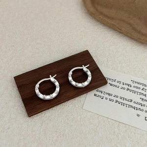 Macro view of 925 sterling silver beaded hoop earrings on a vintage wooden block