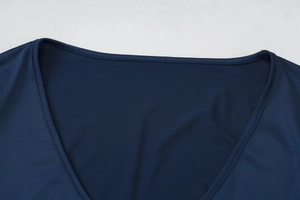 Détail du col en V et des coutures précises sur le haut en maille bleu foncé à manches