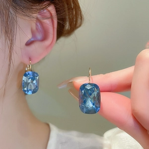 Detailed close-up of French-style gold earrings featuring radiant blue gemstone drops