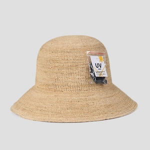 Close-up of the UV protection tag on a wide-brimmed handmade raffia straw summer sun hat