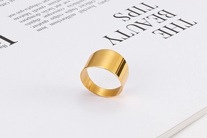 Close-up of minimalist wide gold titanium ring placed on an elegant book page
