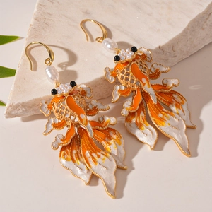 Detail of koi fish earrings with orange enamel and baroque pearls in a traditional style