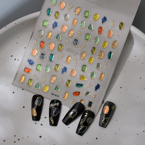 Detailed 3D gemstone nail stickers with gold foil edges shown on black acrylic nails