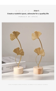 Detail of golden iron ginkgo leaf ornaments with veined texture and wooden base