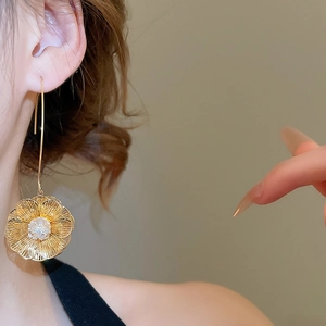 Détail de la boucle d'oreille fleur plaquée or 18K avec zircon portée par un mannequin