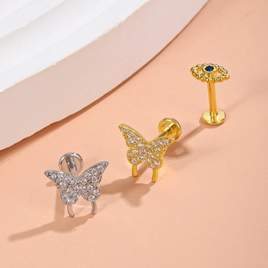 Detail of zircon butterfly and evil eye flat back studs in gold and silver plating