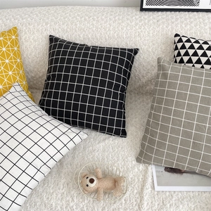Detail of assorted geometric pattern cushion covers on a soft white sofa set