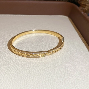 Détail d'un bracelet doré montrant la texture de chaîne creuse et le serti de zircons