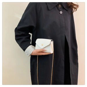 Close-up of white croc-embossed small square bag with golden chain and metallic buckle