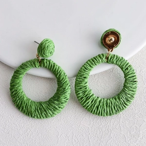 Handmade green raffia woven hoop earrings with floral accents in a bohemian summer style