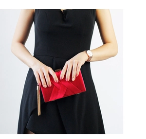 Detail of red satin evening clutch bag with golden metal fringe and elegant tassel