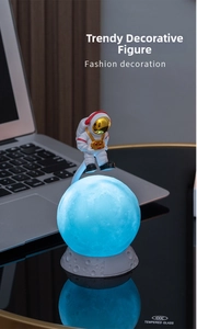 Detail of creative astronaut moon lamp with blue glow and cratered base on desk