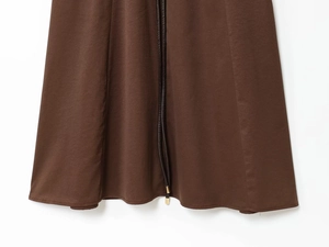 Détail de l'ourlet d'une robe midi marron foncé avec cordons et embouts métalliques dorés