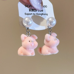Detail of cute pink flocked pig earrings with white semi-round pearls and silver pins