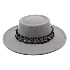 Detalle de sombrero de lana gris con banda decorativa trenzada en negro y plata