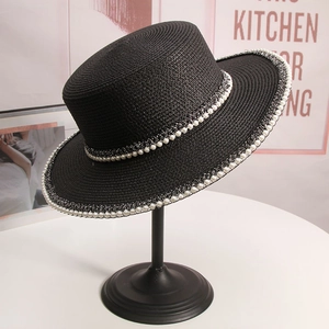 Detail of black straw sun hat with elegant pearl trim on a display stand